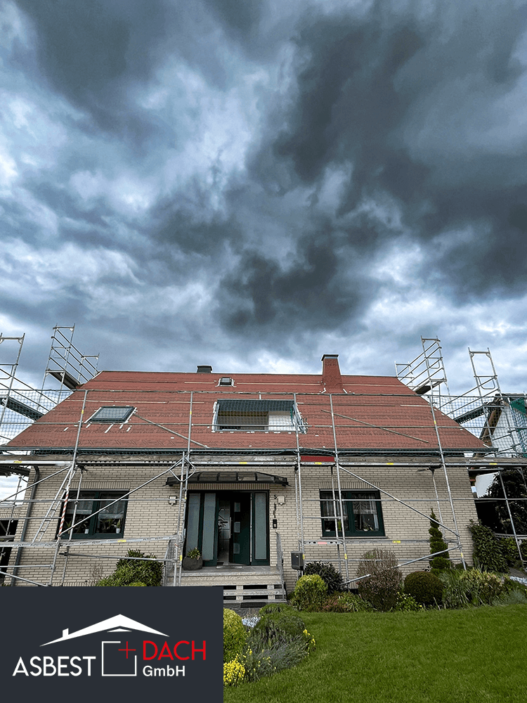 Frisch saniertes Dach nach Asbestsanierung durch Asbest + Dach GmbH, eingerüstetes Einfamilienhaus bei bewölktem Himmel.