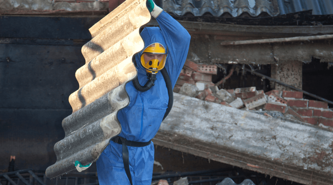 Asbestsanierung Arbeiter Ein Arbeiter trägt einen Schutzanzug und beseitigt Asbestplatten.